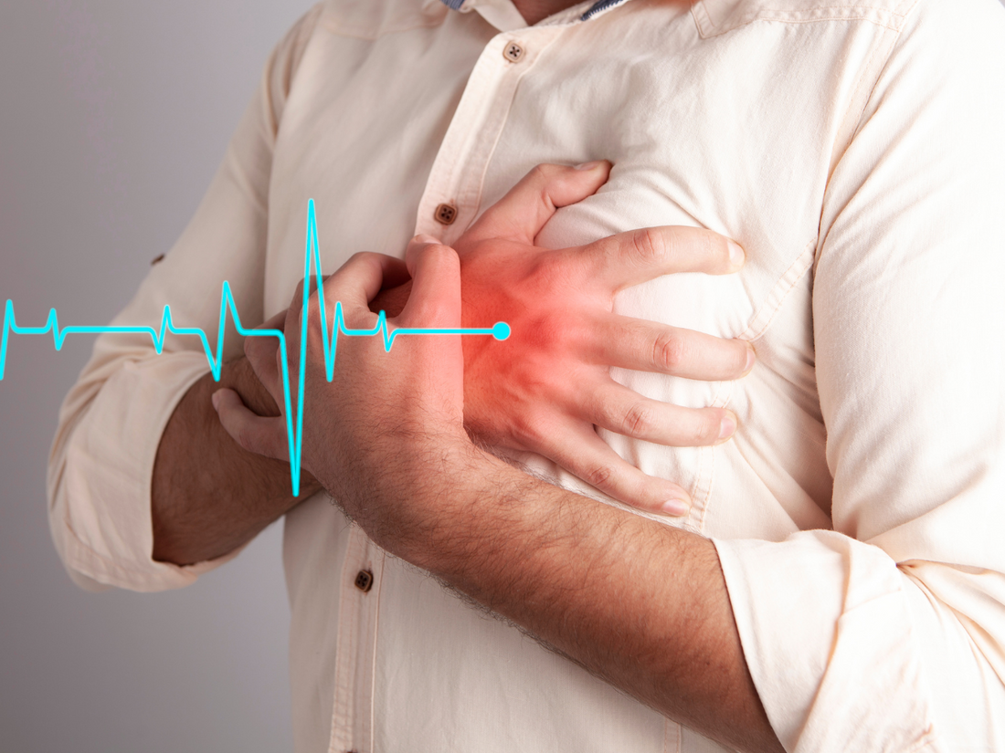 Man in beige shirt clutching chest due to chest pain caused by heart attack