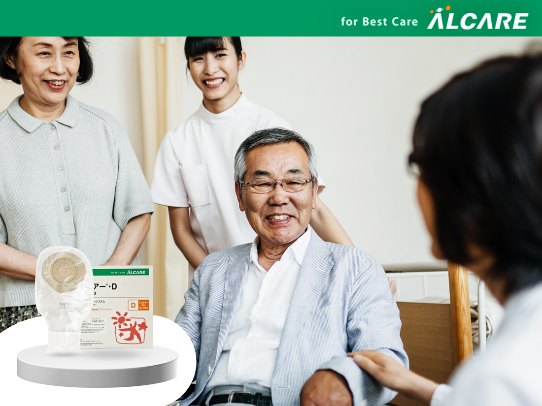 Japanese man seated and smiling as he faces a medical professional, with his wife and daughter standing behind him. ALCARE Youcare D colostomy bag at the bottom left corner of the picture.