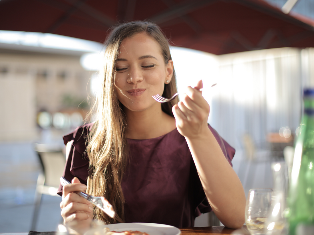 woman enjoying her meal in an outdoor restaurant on a bright, sunny day