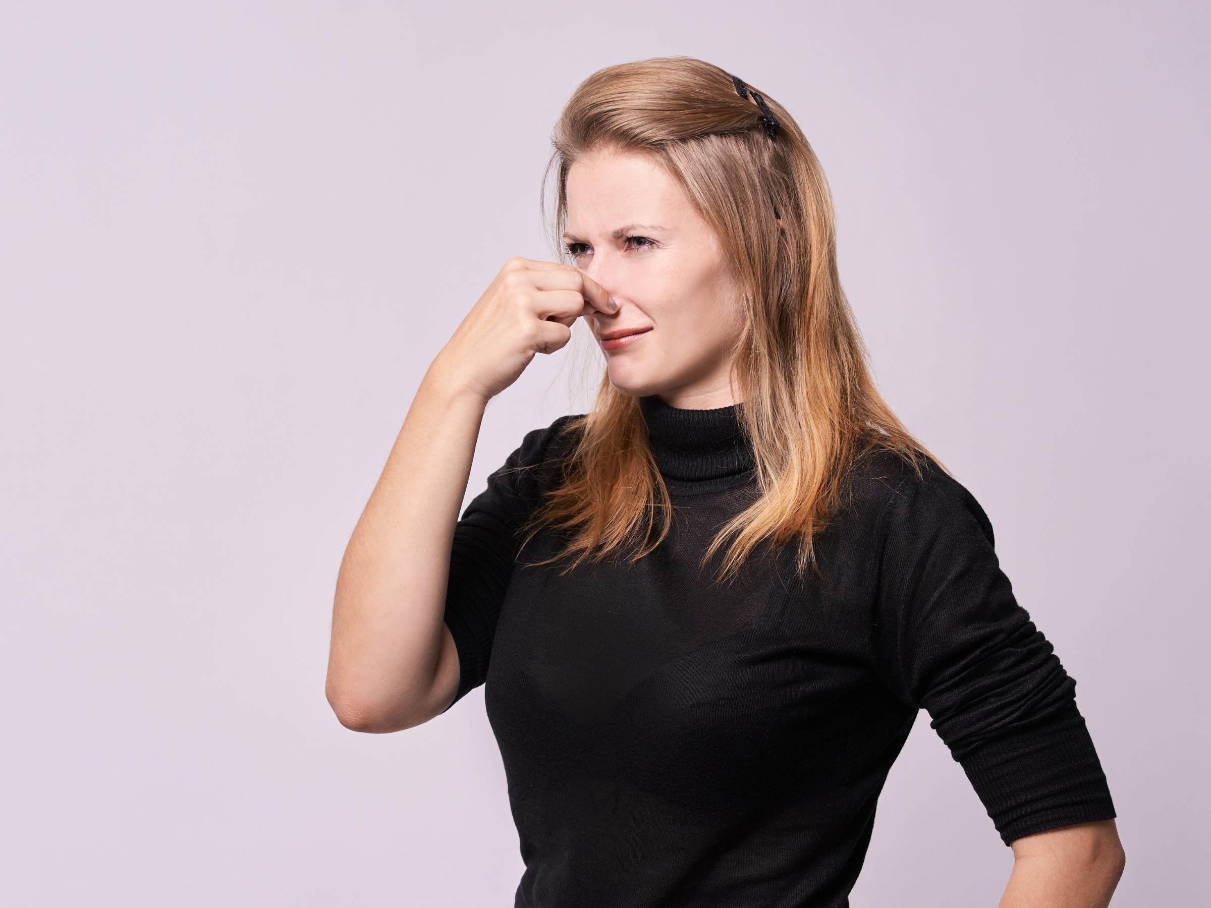 A caucasian lady pinching her nose due to bad odour